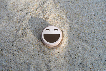 wood smile face on the sand. concept for Service rating, satisfaction concept.