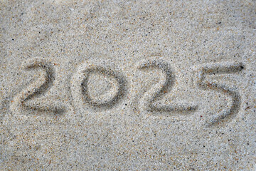 Fototapeta na wymiar handwritten text of 2025 in the sand