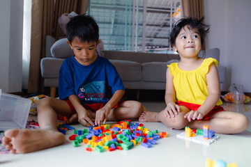Obraz premium Happy adorable kindergarten boy and girl enjoying play toy block building in cozy house