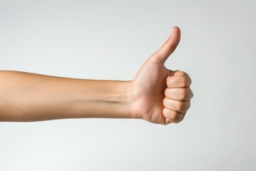 A human hand making a thumbs-up sign against a neutral background