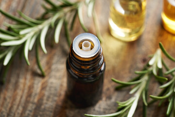 A bottle of aromatherapy essential oil with fresh rosemary plant