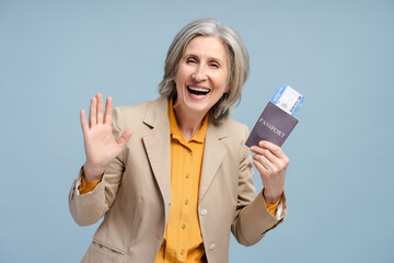 Happy positive gray haired senior woman backpacker holding passport and tickets