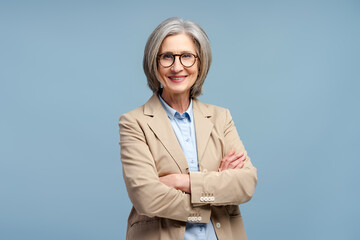 Smiling senior business woman wearing eyeglasses looking at camera, posing arms crossed isolated