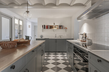 A beautiful, spacious farmhouse-style kitchen with white marble countertop, island with wooden countertop and storage cabinets