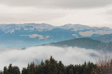 A majestic mountain range is shrouded in a blanket of swirling clouds, creating a mystical and...