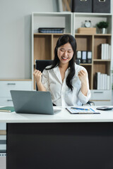 Excited woman work distant on computer talk on cellphone celebrate online win. Happy young female use laptop feel euphoric overjoyed triumph with good news over smartphone call.