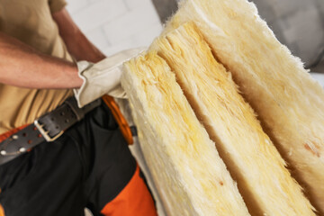 Construction Worker Moving Pieces of Mineral Wool For a House Insulation