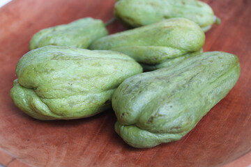 Steamed fruit of small Chayote or Sicyos edule, on wooden plate, isolated on white background