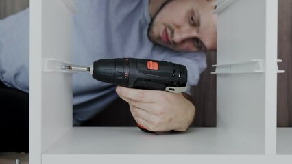 Installation of a drawer on guides in a cabinet. Furniture assembler by handyman.