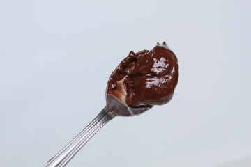 One spoon of melted dark chocolate, or chocolate spread, isolated on white background