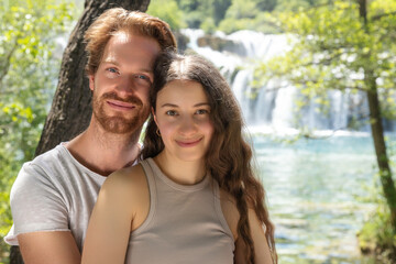 Fototapeta premium The couple of young people in nature park in Croatia. Waterfall on the background.