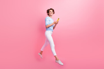 Fototapeta na wymiar Full length profile portrait of energetic carefree person jump use smart phone empty space isolated on pink color background