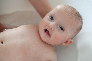 Little baby is being bathed by his mother. Cute baby during bath time