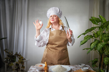 A fat funny female cook in a hat and apron poses in the kitchen and takes a selfie. Good cooking...