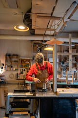 Carpenter prepares equipment for work. Smiling man guy with wrench busy organizing workspace workplace, putting things in order. Strict working day structure of joiner woodworker master.