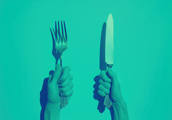 Fototapeta premium Two hands holding knife and fork in front of turquoise background, one hand with knife and fork, the other with knife and fork