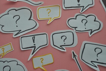 top view of of black question and exclamation mark on white speech bubble on a pink background.