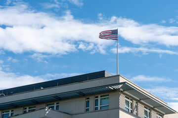 Waving American flag against a blue sky. American flag on the roof of the building.
