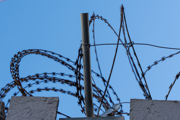 Barbed wire on top of a fence against a blue sky. Freedom concept.