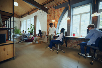 Interactive co-working space. Bustling co-working environment with young multiethnic people working...