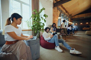 Young entrepreneurs and students in co-working space working and cooperating. Cozy, comfortable...