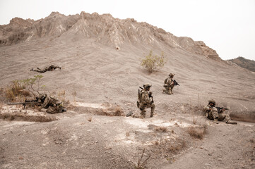 Naklejka premium Soldiers in camouflage uniforms aiming with their rifles.ready to fire during military operation in the desert , soldiers training in a military operation