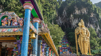 The famous Batu caves. Many people climb the rainbow-colored stairs to the shrine. A huge golden...