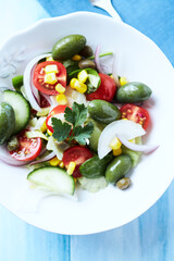 Simple Salad with Green and Kalamata Olives, Cucumber, Cherry and marinated Tomatoes, Capers and Jalapeno Pepper. Bright wooden background.	Top view. 