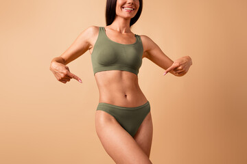 Cropped no retouch photo of adorable happy strong girl showing her thin waist gym exercises diet sport isolated on beige color background