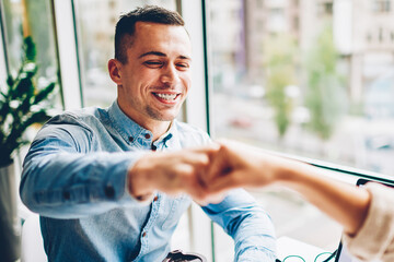 Cheerful male employee bumping fist making gesture of agreement satisfied with collaboration process,cropped image happy businessman knuckles with colleague making deal during planning startup - Powered by Adobe