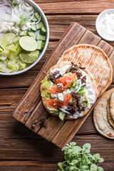 Greek gyros wrapped in pita breads on a wooden background