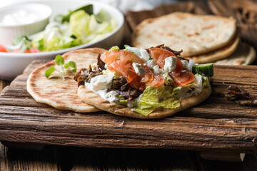 Greek gyros wrapped in pita breads on a wooden background