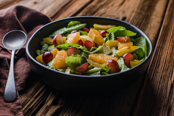 Vegetable salad with pomegranate seeds on a bright metal background, top view. Lettuce, corn salad, cucumber, avocado, orange, pomegranate.