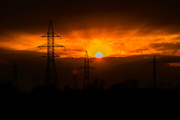 High voltage power line at sunset. Silhouettes of the metal pillars