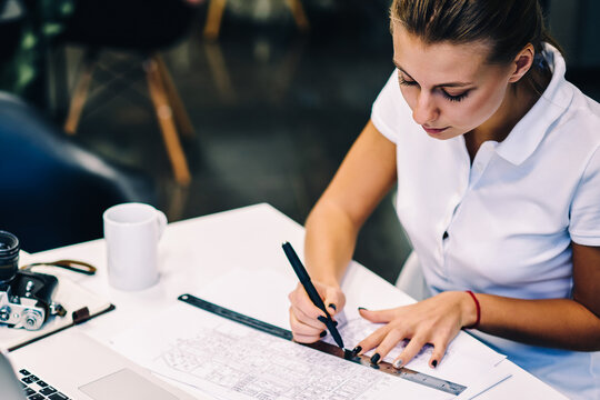 Professional female architect drafting blueprint accountings using ruler at desktop with netbook, clever woman drawing table for organizing working schedule fillin with information about tasks - Powered by Adobe