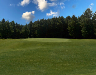 Fototapeta premium A beautiful view of lush green golf course surrounded by beautiful hills with pine trees at Pahalgam Kashmir India.
