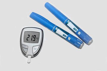 Blood sugar meter with test strips indicates high blood sugar levels and injection pen for diabetes.