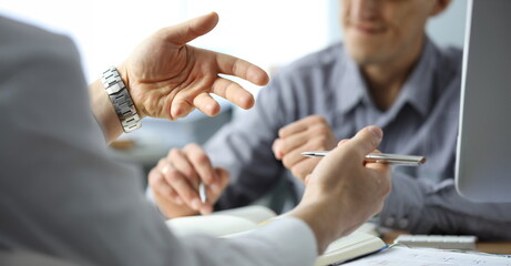 Close-up of gesturing male hands. Businessman explaining project details to partner in office. Conference of people brainstorming on development of company. Boss and employee wearing watch - obrazy, fototapety, plakaty