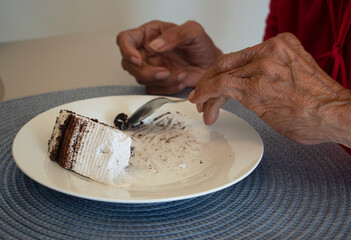 the hand of an old woman eating cake