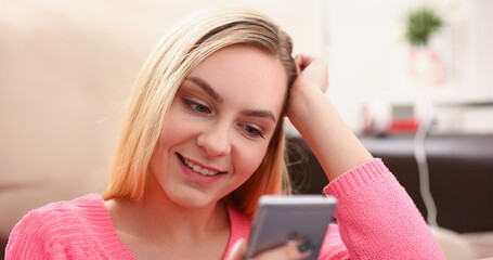 young pretty blond womansit on sofa hold smartphone in hands chat with friends - obrazy, fototapety, plakaty