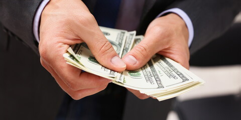 Man in suit and tie hold in arm pack of hundred dollar bills closeup. Stock market exchange earn...