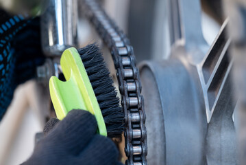 Male hands in gloves cleaning the chain of motorcycle, close up. Motorcycle maintenance, care of...