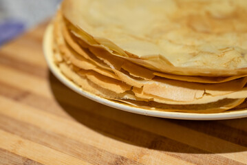 Close up of a tasty yellow crepes with crispy edges on a white plate. Concept of homemade food, sweets and dessert