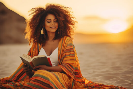 Beautiful African American Wiccan woman sits on the beach and reads a book.