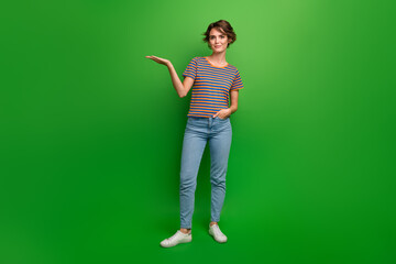 Full body portrait of gorgeous positive lady arm palm hold demonstrate empty space isolated on green color background