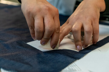 Close up view of tailor's hand marking sewing pattern on fabric with soap.