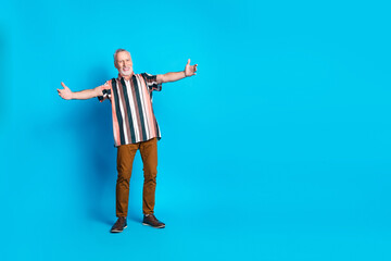 Full length photo of glad positive senior man wear striped trendy clothes empty space isolated on blue color background