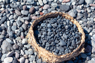 Containers with small pebbles collected from the ground by women at Kusamba Beach in Bali, Indonesia.
