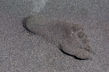 Human footprint in the black sand of Kusamba beach in Bali Indonesia.