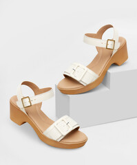 Sophisticated white textured buckle sandals for women, elegantly displayed on geometric Cubic...